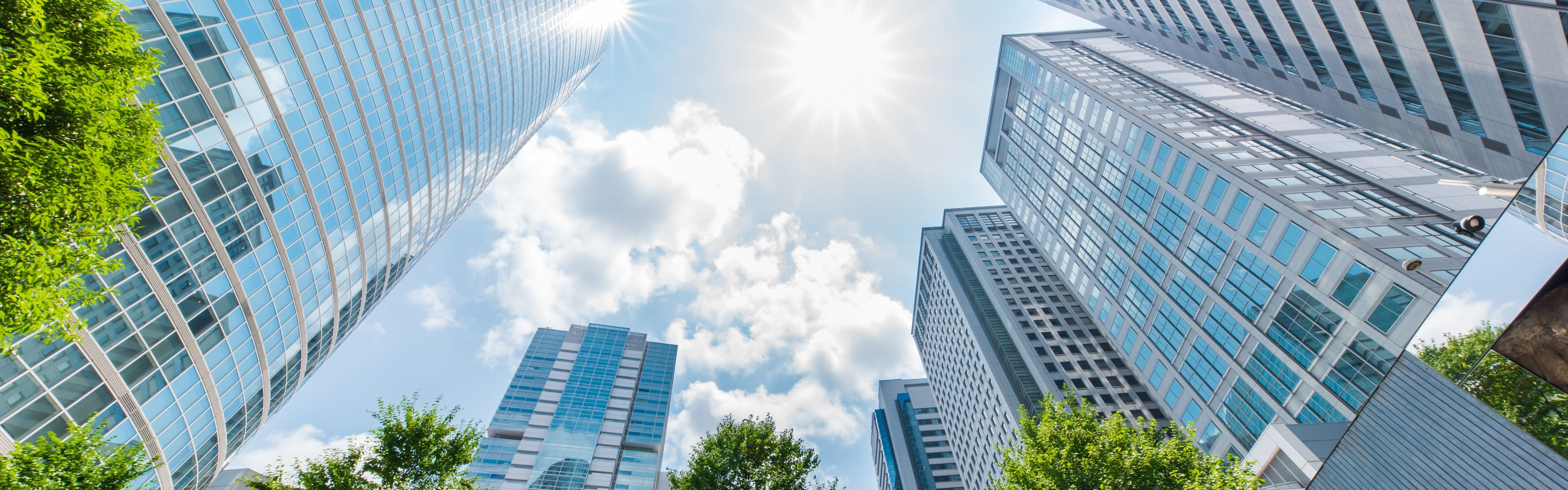 太陽の光がまぶしく輝き、雲が点在する爽やかな日中の景色
