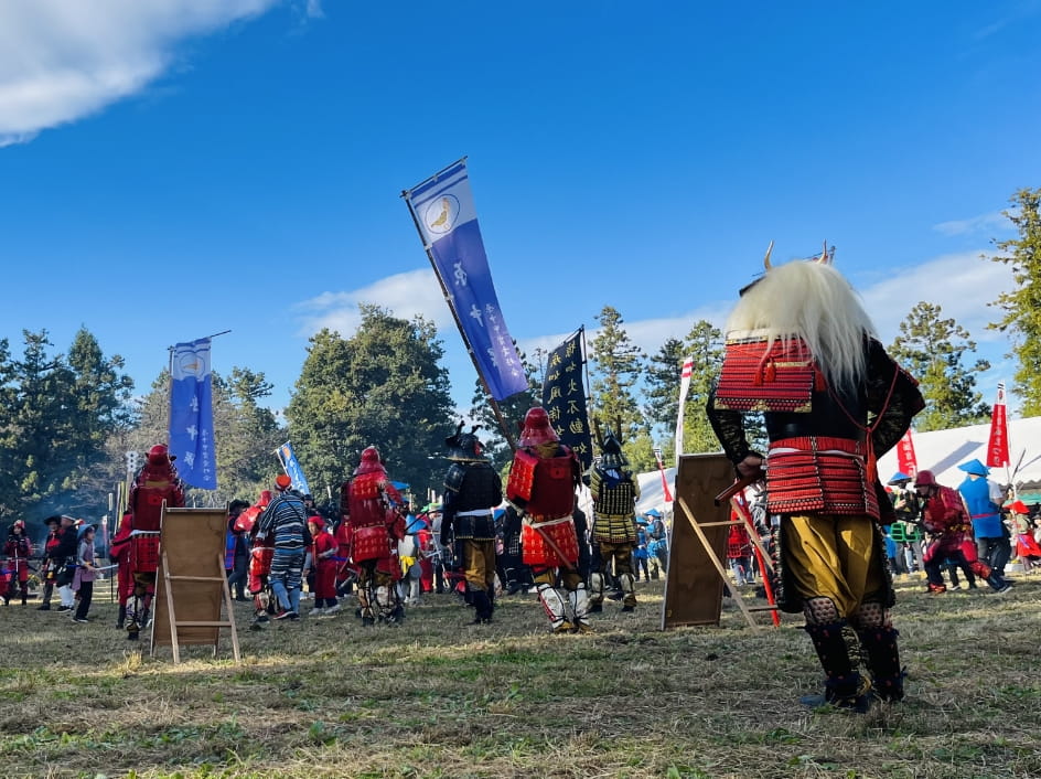 鎧兜を身につけた人々が広場で集まり、戦国時代を再現したイベントの様子